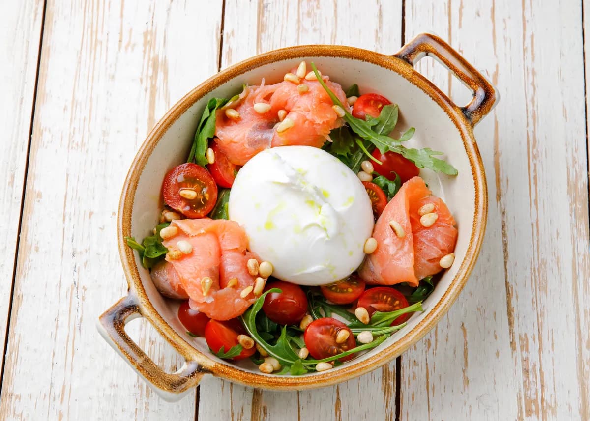 Salad with burrata cheese, smoked salmon, and pine nuts
